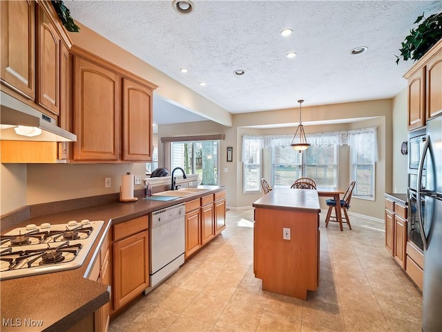 kitchen with a sink, under cabinet range hood, a center island, white appliances, and hanging light fixtures