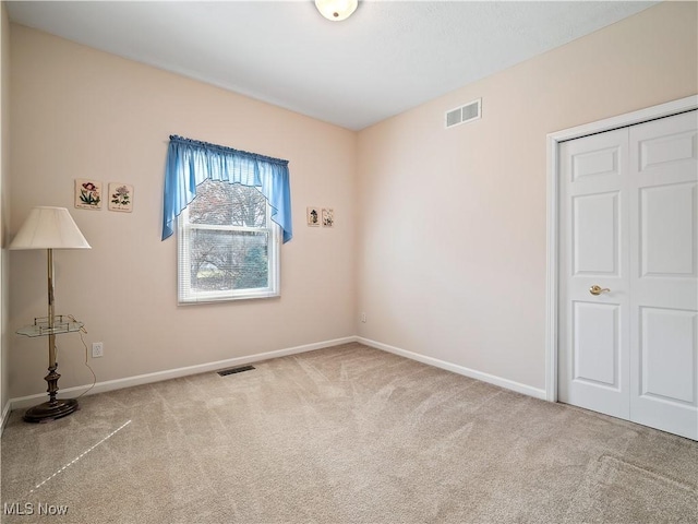 carpeted empty room with visible vents and baseboards