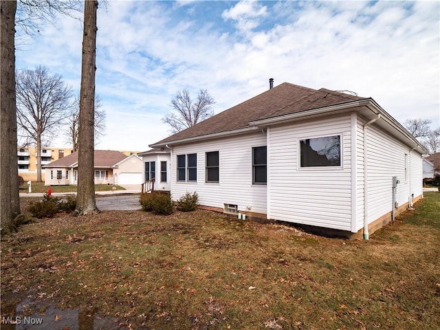 back of property with a yard and roof with shingles