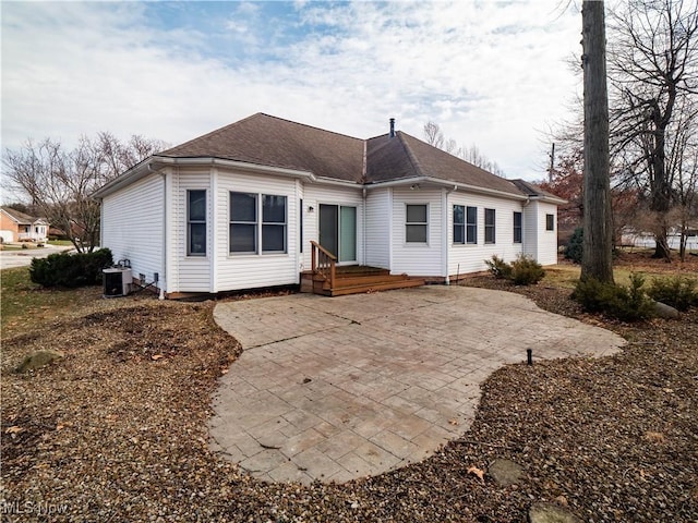 rear view of house featuring a patio, central AC unit, and roof with shingles