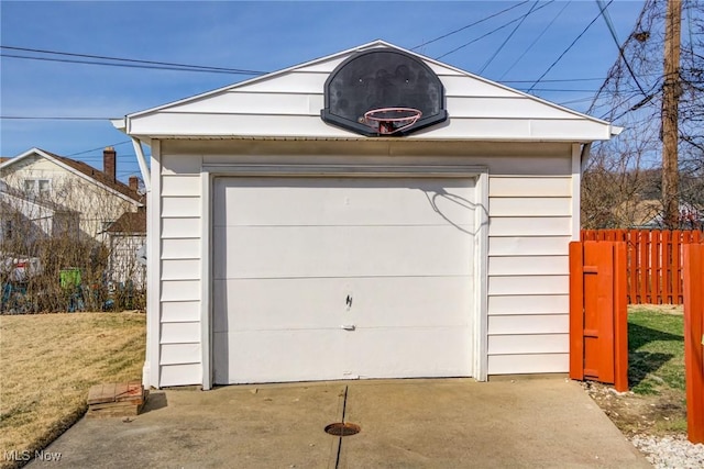 detached garage featuring driveway and fence