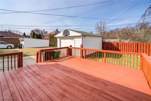 wooden terrace featuring a garage, a yard, an outdoor structure, and fence