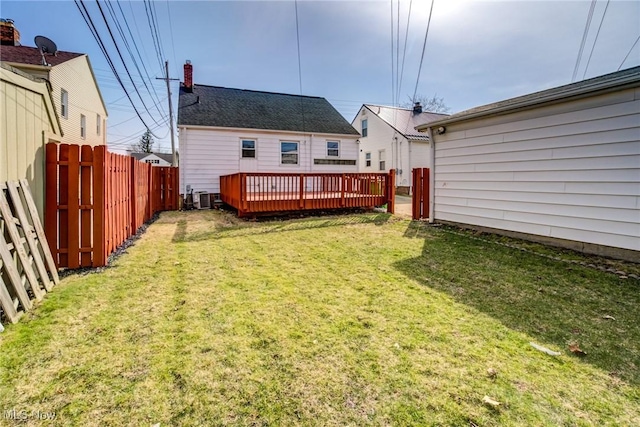 rear view of property featuring central air condition unit, a lawn, fence private yard, and a deck