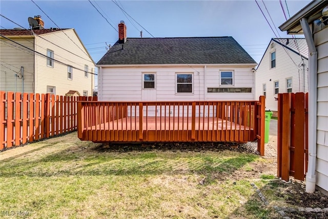 exterior space featuring a yard, a wooden deck, a fenced backyard, and roof with shingles