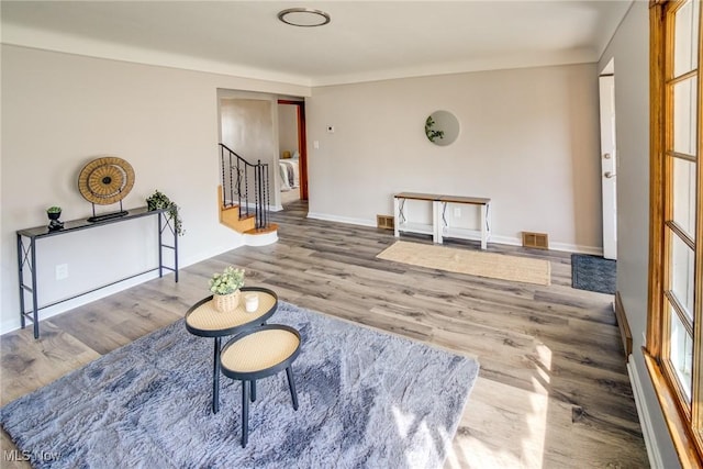 sitting room with stairway, wood finished floors, visible vents, and baseboards