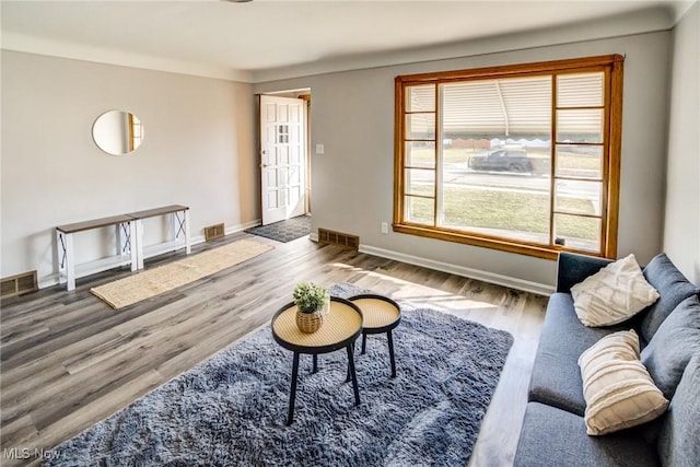 living area featuring visible vents, baseboards, and wood finished floors