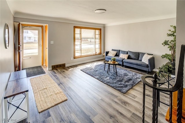 living room featuring visible vents, baseboards, and wood finished floors