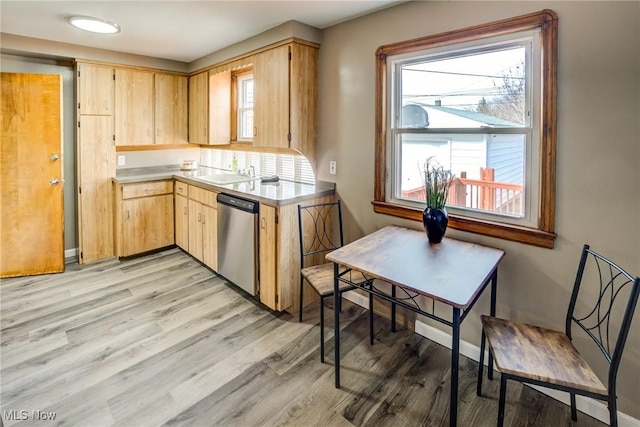 kitchen with light brown cabinetry, dishwasher, light countertops, light wood-style floors, and a sink