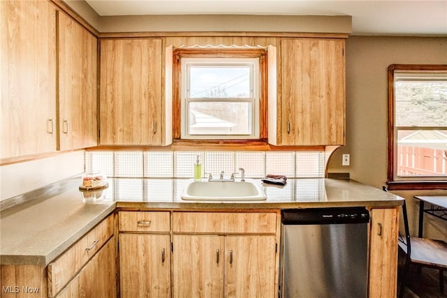 kitchen with stainless steel dishwasher, light countertops, light brown cabinetry, and a sink