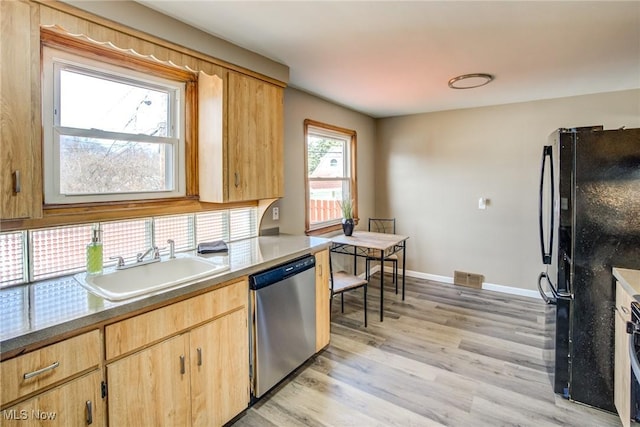 kitchen featuring visible vents, freestanding refrigerator, a sink, light wood-style floors, and stainless steel dishwasher