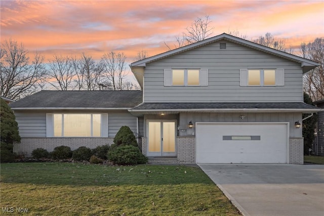 traditional-style house with brick siding, an attached garage, concrete driveway, and a front yard