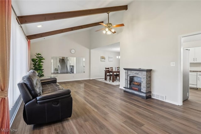 living room featuring visible vents, baseboards, beam ceiling, a stone fireplace, and wood finished floors