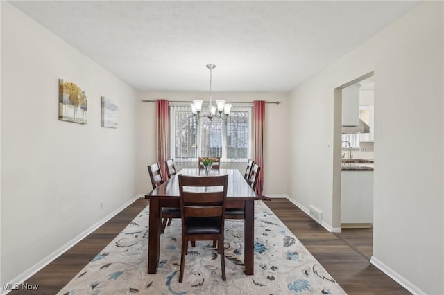 dining room with an inviting chandelier, dark wood-type flooring, visible vents, and baseboards