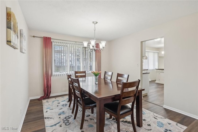 dining area featuring baseboards, plenty of natural light, an inviting chandelier, and wood finished floors