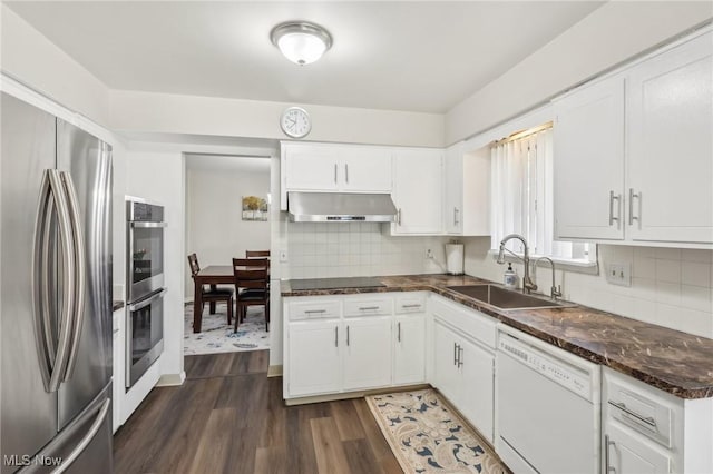 kitchen with a sink, stainless steel appliances, dark wood-type flooring, under cabinet range hood, and backsplash