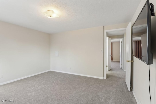 empty room with carpet flooring, baseboards, and a textured ceiling