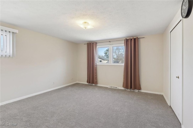 unfurnished bedroom featuring visible vents, a textured ceiling, a closet, carpet, and baseboards