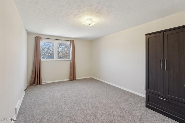 unfurnished bedroom featuring visible vents, baseboards, light colored carpet, and a textured ceiling