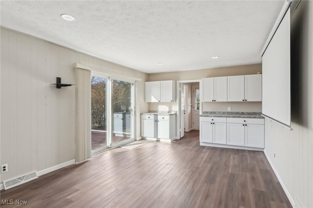 kitchen featuring white cabinetry, wood finished floors, visible vents, and baseboards