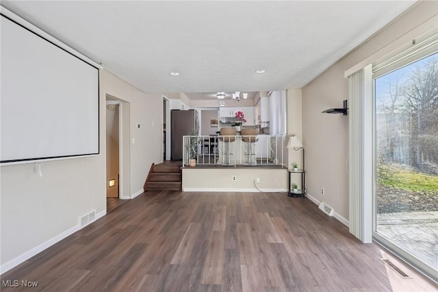 unfurnished living room with visible vents, baseboards, and wood finished floors