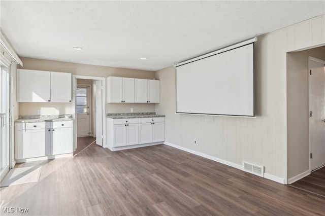 kitchen with visible vents, baseboards, wood finished floors, and white cabinetry