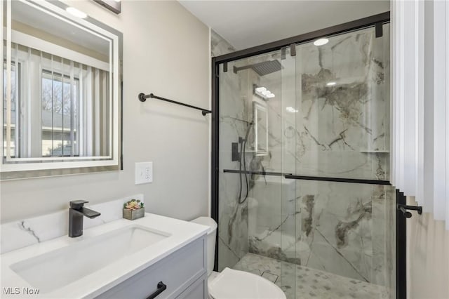 bathroom featuring a marble finish shower, toilet, and vanity