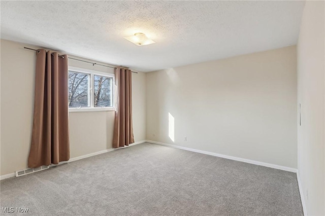 carpeted empty room with visible vents, baseboards, and a textured ceiling