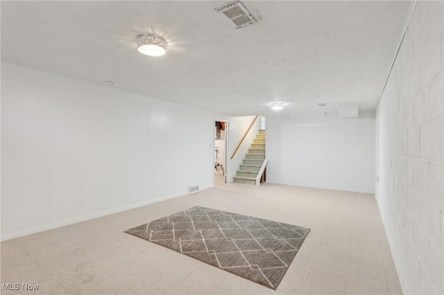 finished below grade area with visible vents, baseboards, concrete block wall, and stairway