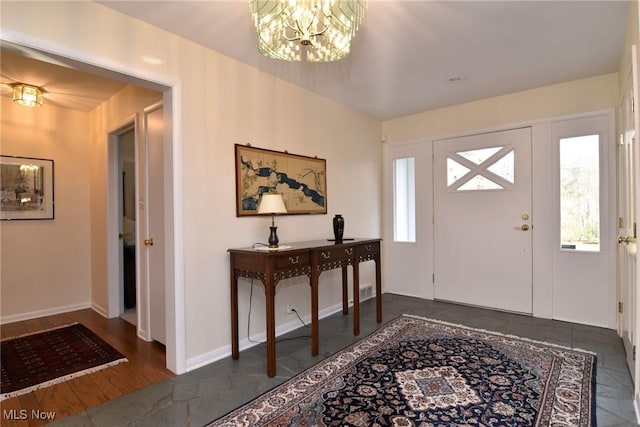 foyer entrance featuring baseboards, a notable chandelier, and a healthy amount of sunlight