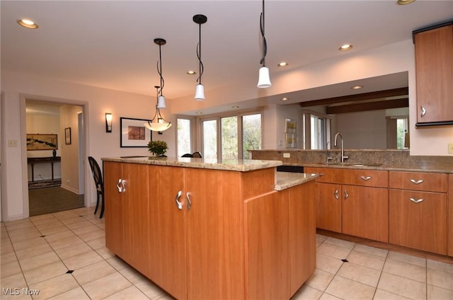 kitchen featuring recessed lighting, light stone countertops, a center island, and a sink