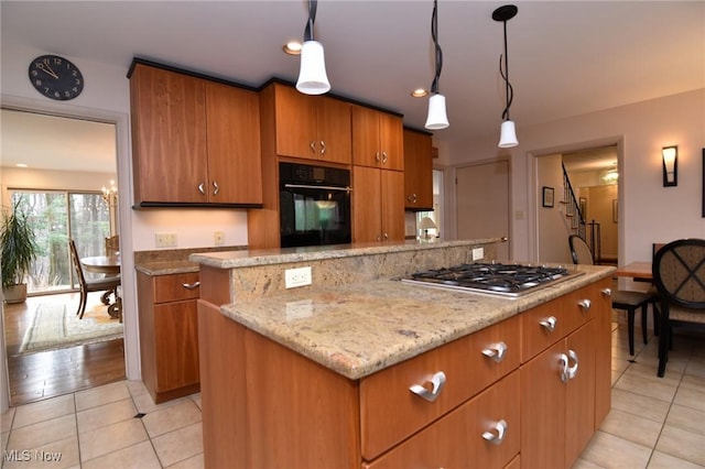 kitchen with stainless steel gas stovetop, light tile patterned floors, pendant lighting, and oven