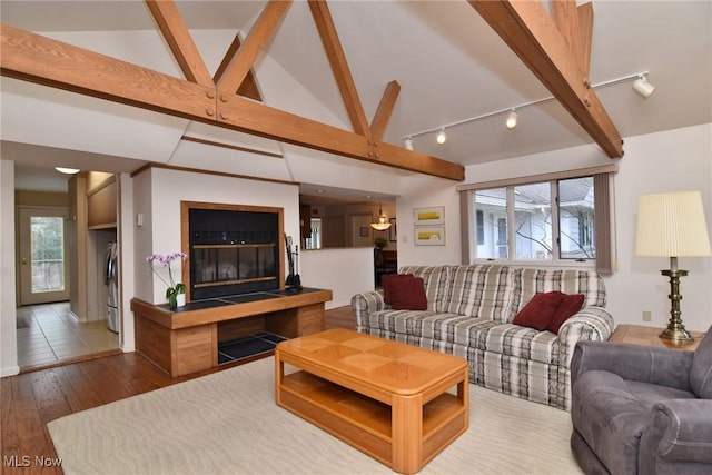 living area with washer / clothes dryer, vaulted ceiling with beams, and wood-type flooring