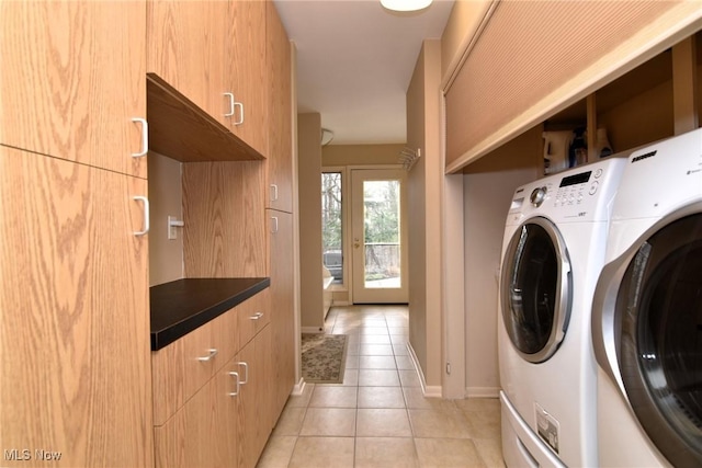 laundry area with light tile patterned floors, cabinet space, and washer and clothes dryer