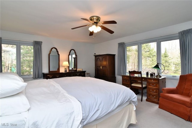 bedroom featuring a ceiling fan, multiple windows, and light colored carpet