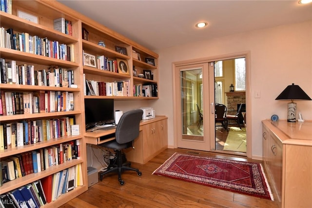 home office with recessed lighting, french doors, a stone fireplace, and wood finished floors