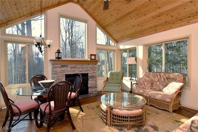 living area with a stone fireplace, plenty of natural light, wood ceiling, and high vaulted ceiling