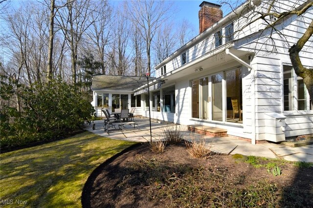 back of house with a patio, a yard, and a chimney