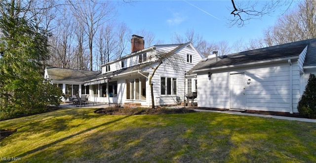 rear view of property with a yard, a chimney, and a patio