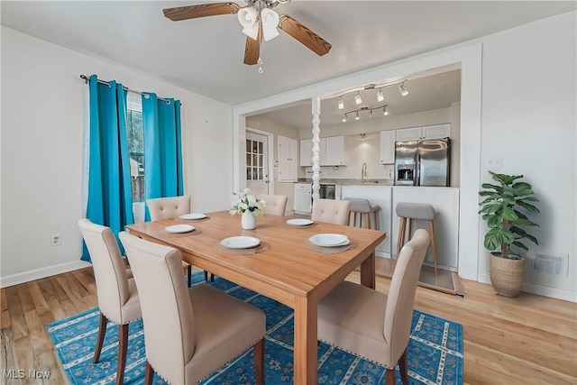 dining area with light wood-style flooring, visible vents, and baseboards