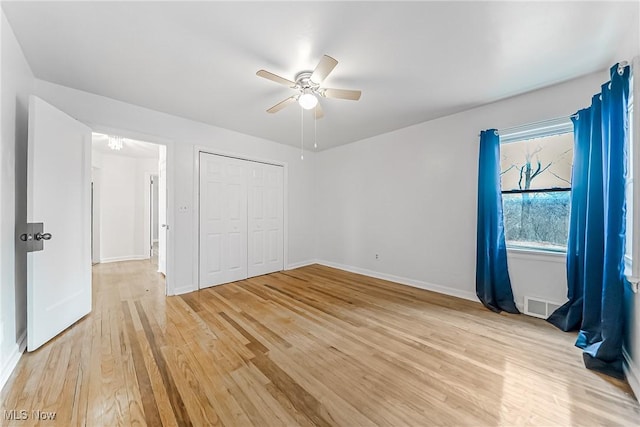 unfurnished bedroom featuring visible vents, ceiling fan, baseboards, light wood-type flooring, and a closet