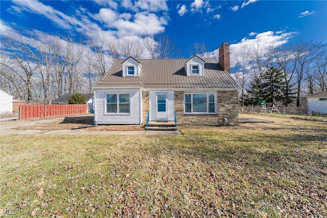 new england style home with stone siding, a chimney, a front lawn, and fence