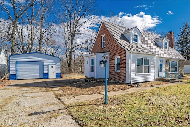 view of side of property featuring an outbuilding, driveway, a chimney, a garage, and metal roof