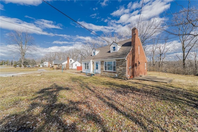 view of front facade featuring a front yard, stone siding, and a chimney