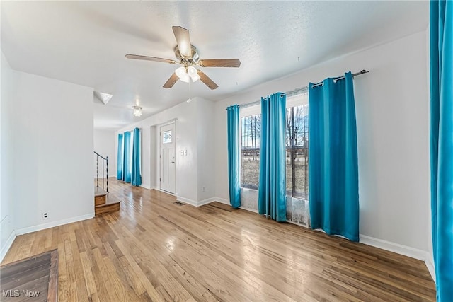 spare room featuring stairway, a ceiling fan, baseboards, and wood finished floors