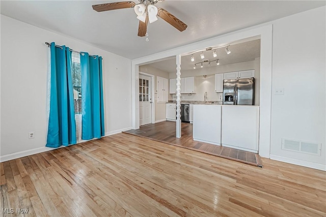 unfurnished living room featuring visible vents, light wood-type flooring, and a ceiling fan