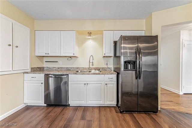 kitchen featuring baseboards, a sink, dark wood-type flooring, white cabinets, and appliances with stainless steel finishes