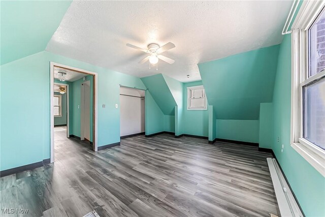 bonus room featuring a ceiling fan, wood finished floors, baseboards, lofted ceiling, and a textured ceiling