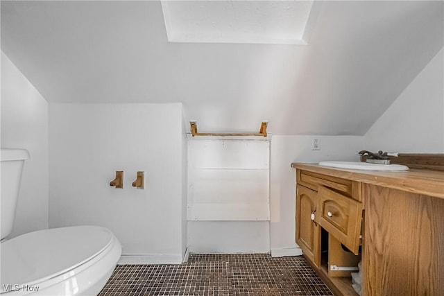 bathroom featuring toilet, vanity, and vaulted ceiling