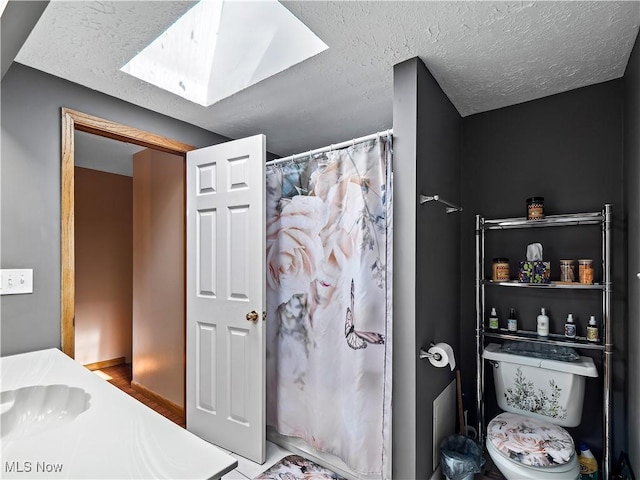 bathroom with a shower with curtain, wood finished floors, a textured ceiling, and a skylight