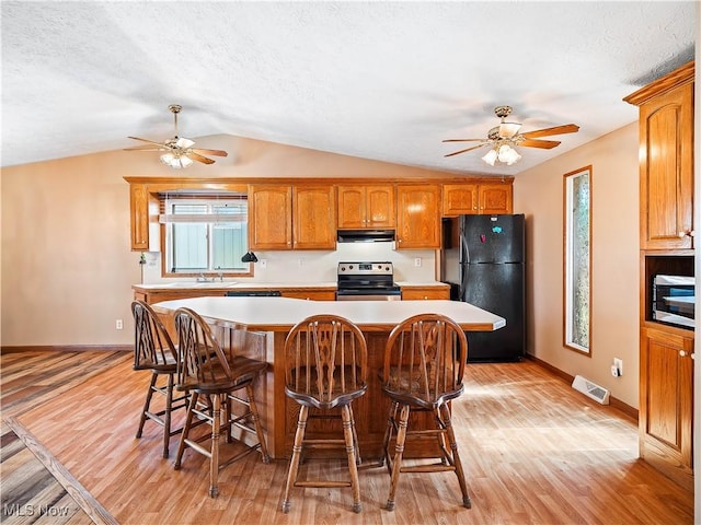 kitchen featuring under cabinet range hood, stainless steel appliances, light wood-style floors, and light countertops